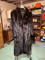 Front view of full-length dark brown mink coat on hanger
