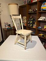Front view of distressed white wooden children’s chair on table