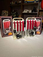 Front view of both cutlery sets on stands with boxes behind