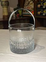 Front view of clear glass ice bucket showing ribbed base and handle