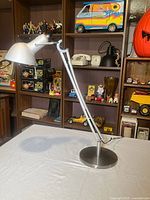 Full view of articulated aluminium Lumina Naomi lamp on table