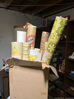 Box containing eight vintage wallpaper rolls with varied patterns