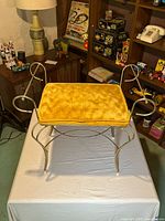 Front view of vanity bench showing scroll arms, velvet seat, metal frame