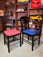 Both wrought iron chairs side-by-side showing red and blue seats and decorative backs