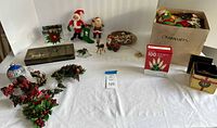 Table layout showing plush Santas, nativity set, plate, ornaments, lights, stocking and gift boxes