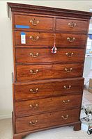 Full front view showing entire highboy dresser, drawer layout, brass pulls, dentil molding, bracket feet