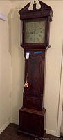 Full view of mahogany longcase clock showing hood, trunk and base