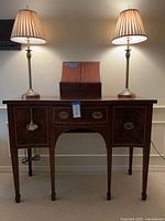 Front view of mahogany sideboard with two brass lamps and wood organizer on top