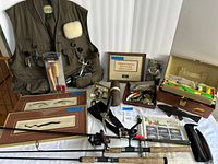 Overall view showing vest, rods, reels, tackle boxes, framed prints and tools