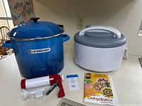 Stockpot, dehydrator, jerky tool, booklet grouped on countertop