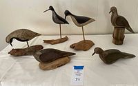 All seven carved wooden shorebird decoys on display table
