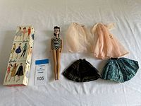 Full lot showing Barbie doll, box lid, four additional garments laid out