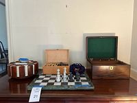 Overview showing poker chip carousel, small wooden box with game pieces, marble chess board with pieces, large felt-lined wood box