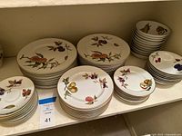 Stacks of Royal Worcester Evesham plates and bowls on shelf