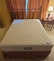 Full view of mattress on frame with metal headboard visible