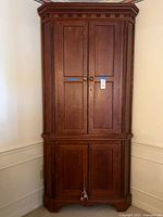 Full view of closed solid wood corner hutch showing upper and lower doors and dentil crown