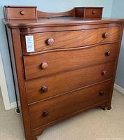 Front view of hardwood dresser showing four drawers, two valet drawers on top surface, serpentine front