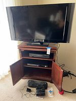 Overall view of TV on cabinet with doors open showing AV components inside and accessories in front