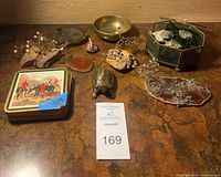 Full lot overview showing fossil plaque, brass bowl, agate slices, wire trees, turtle figurine, pendant, coasters, glass box