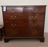 Front view of wooden chest showing all drawers and hardware