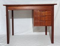 Front view showing teak desk, top, legs, and drawer bank