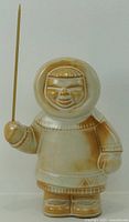 Front view of glazed ceramic Inuit figure holding wooden stick