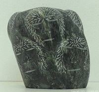 Front view of basalt carving showing incised detailing of Inuit family figures