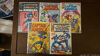 Five Captain America comics laid out showing front covers