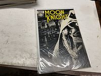 Front view of bagged Moon Knight #23 comic on tabletop