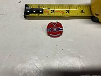 Front view of enamel jersey pin with measuring tape indicating size