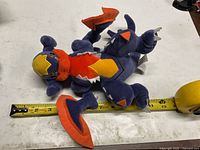 Top view of Mega Garchomp plush next to tape measure