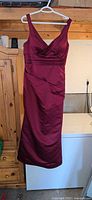 Front view of burgundy sleeveless V-neck dress hanging on hanger