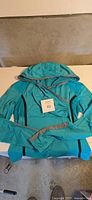 Full view of turquoise Lululemon hooded jacket laid flat