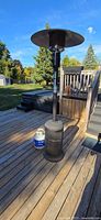 Full view of patio heater standing on deck with one propane tank beside base