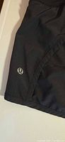 Front view of black Lululemon shorts showing logo on left leg