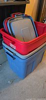 Stacked view of blue tote with red tote nested inside and grey lids visible