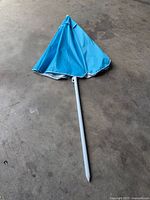 Umbrella folded with pole attached, showing tip and fabric