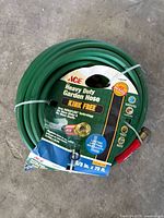 Coiled green Ace heavy duty garden hose with sleeve showing specs