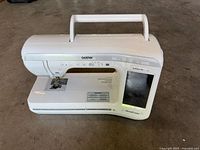 Front view of Innovis VQ2400 sewing machine showing controls, LCD screen, and needle area