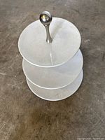 Three-quarter view of white glazed stoneware lid showing metal knob