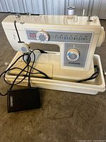 Front view of sewing machine with foot pedal and base of carry case