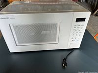 Front view of Sharp Carousel microwave showing control panel, door, and power cord