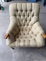 Front view of tufted beige lounge chair showing wooden arms and legs