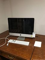 Front view of Apple iMac with keyboard, trackpad and power cord