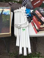 Disassembled white rack tubes and caster bases on table with two folded umbrellas