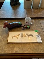 All four items: framed print, wooden dachshund, ceramic dachshund, ceramic mug