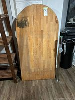 Front view of wood table top leaning against wall, metal leg at side