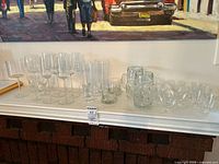 Group of assorted stemware, tumblers, highballs and beer mugs on mantle