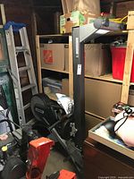 Rowing machine folded upright in garage showing arm and monitor mount