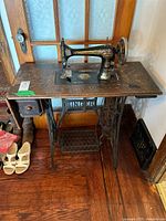 Front angle of Singer treadle machine showing sewing head, cabinet top, and cast iron base